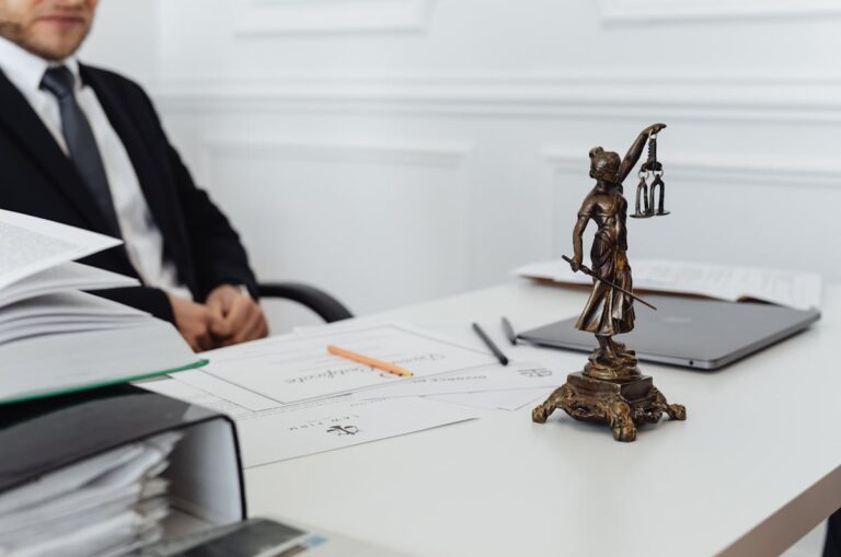 A legal professional's workspace featuring Lady Justice statue, documents, and a laptop.