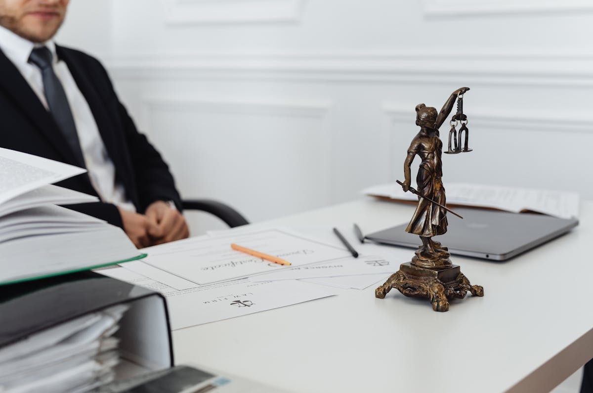 A legal professional's workspace featuring Lady Justice statue, documents, and a laptop.