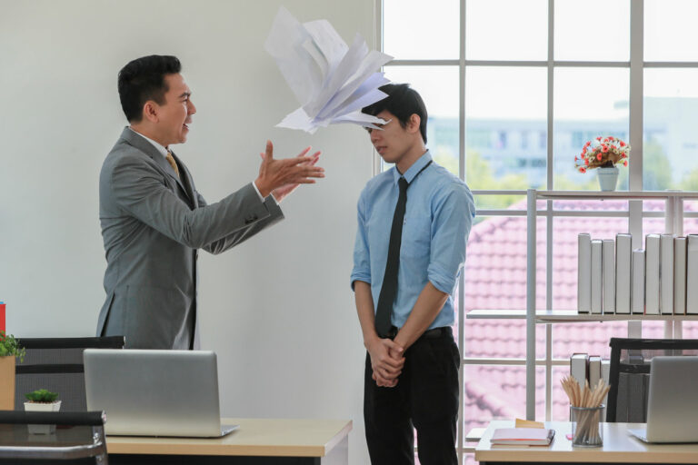 Asian businessman manager in suit throwing paperwork into air and blaming for young employee with anger and serious gesture. Office work problem and job quality conflict concept