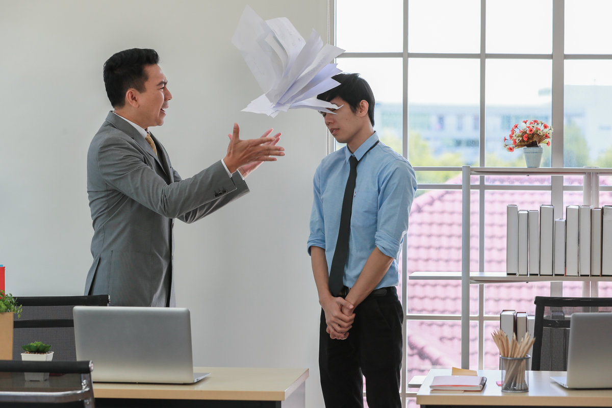Asian businessman manager in suit throwing paperwork into air and blaming for young employee with anger and serious gesture. Office work problem and job quality conflict concept